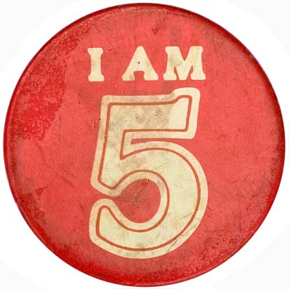 A photograph of a red badge on a white background. The badge says 