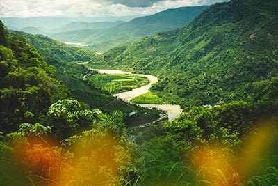 Cultivated valley amid forested hills.